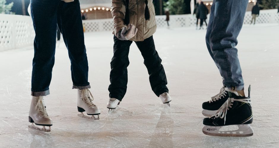 the legs and feet of three people on an ice rink while wearing ice skates