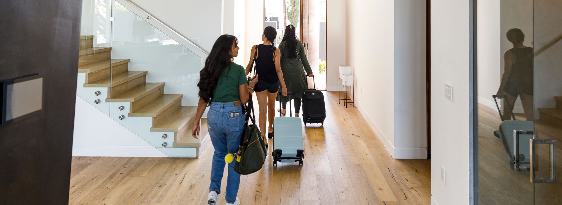 Three woman holding bags and suitcases while leaving a vacation rental.